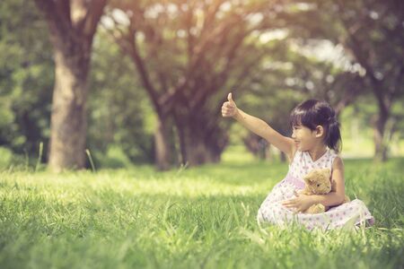 little girl holds the thumb up in park.Vintage Colorの写真素材