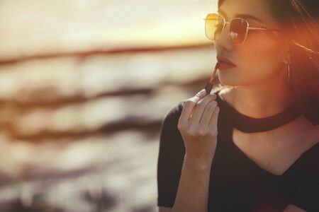 sexy woman making make-up woman applying lipstick outdoors.retro colorの写真素材