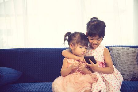 Children listening to music while sitting on a couchの写真素材