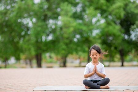 Little cute asian girl practicing yoga pose on a mat in park, Healthy and exercise conceptの写真素材