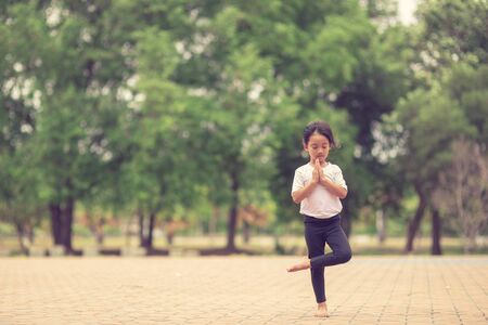 Little cute asian girl practicing yoga pose on a mat in park, Healthy and exercise conceptの写真素材