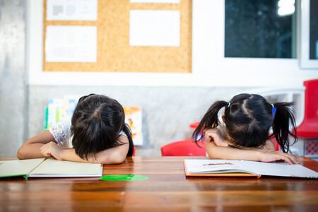 Sleepy pupils napping at desks in classroom at the elementary schoolの写真素材