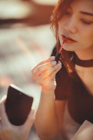 sexy woman making make-up woman applying lipstick outdoors.retro color