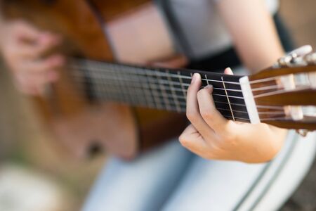 Lovely girl,playing guitar, singing ,music or happiness concept, sunset warm light tone effect.