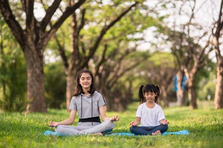Two cute girls practicing yoga at parkの写真素材
