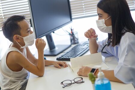 An Asian female doctor wearing a surgical mask is pouring alcohol gel on the patient's hand.