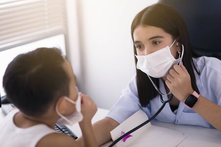An Asian female doctor wearing a surgical mask is pouring alcohol gel on the patient's hand.