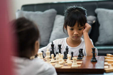 Two cute children playing chess at homeの写真素材