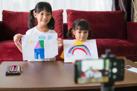 Two asian child girl students study online with teacher by video call together.
