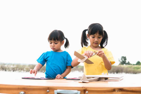 Two little kids playing with cardboard toy airplane in the park at the day time. Concept of happy game. Child having fun outdoors.の写真素材