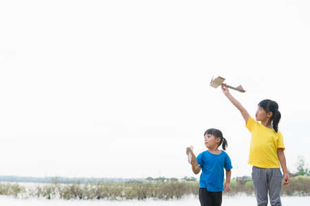 Two little kids playing with cardboard toy airplane in the park at the day time. Concept of happy game. Child having fun outdoors.の写真素材