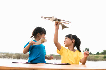Two little kids playing with cardboard toy airplane in the park at the day time. Concept of happy game. Child having fun outdoors.の写真素材