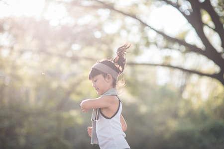 happy child girl running in the park in summer in nature. warm sunlight flare. asian little is running in a park. outdoor sports and fitness, exercise and competition learning for kid development.の写真素材