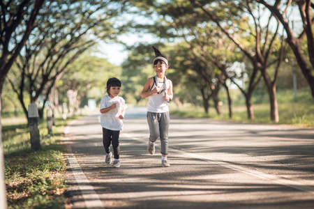 Two asian little girls having fun and running together in the park in vintage color toneの写真素材