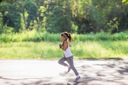 happy child girl running in the park in summer in nature. warm sunlight flare. asian little is running in a park. outdoor sports and fitness, exercise and competition learning for kid development.の写真素材