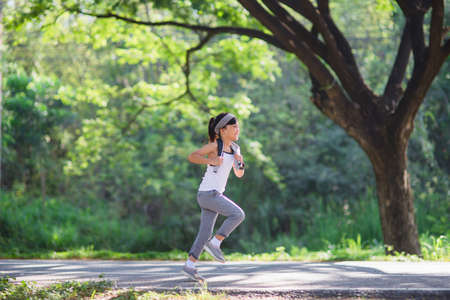happy child girl running in the park in summer in nature. warm sunlight flare. asian little is...
