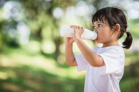 Cute asian little child girl is drinking a milk, soft focusの写真素材