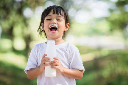 Cute asian little child girl is drinking a milk, soft focusの写真素材