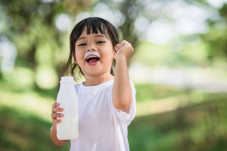 Cute asian little child girl is drinking a milk, soft focusの写真素材
