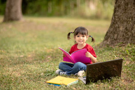 Cute Little Girl Reading Book Outside on Grass