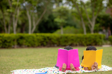 two beautiful little girls reading books in the garden , sitting on grass. The concept of education...