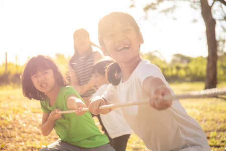 Children playing tug of war at the park on sunsutの写真素材