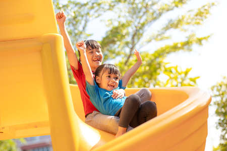 Cute little girls siblings having fun on playground outdoors on sunny summer day. Children on...