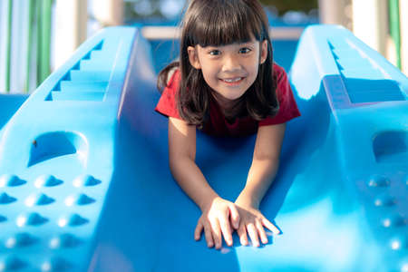 Cute little girl having fun on a playground outdoors in summerの写真素材