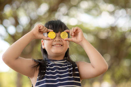 Asian Little Girl holding bitcoin digital money. Concept of easy bitcoin investing and trading. Close-up.の写真素材