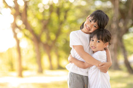 Two asian little child girls hugging each other with love in the garden iの写真素材
