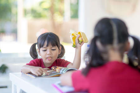 Asian children in the canteen having lunch or breakfast are having funの写真素材