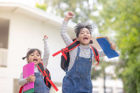 Children with rucksacks jumping in the park near school. Pupils with books and backpacks outdoorsの写真素材