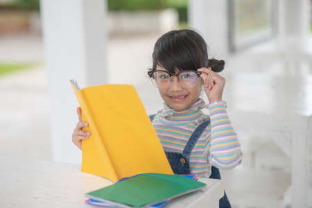 Happy Asian girl reading a book on the table