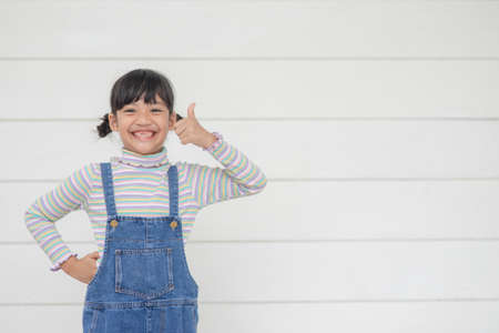 Portrait of little cute Asian girl with her thump up, advertisement concept, little Asian teenage...