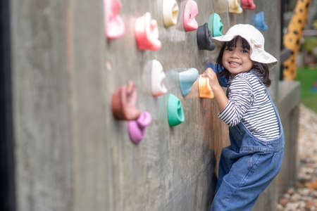 Asian little girl climbing a rock wall