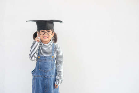 Happy Asian school kid graduate thinking with graduation capの写真素材