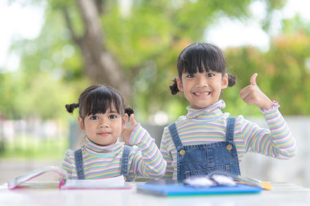 Two student little Asian girls reading the book on tableの写真素材