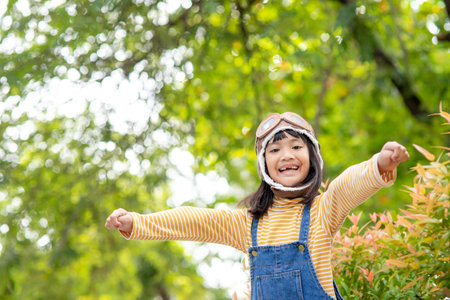 A cute little girl dressed in a cap and glasses of a pilot. The child dreams of becoming a pilot.