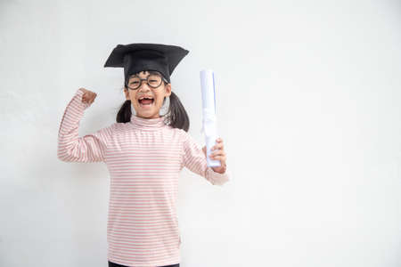 Happy Asian school kid graduate in graduation capの写真素材