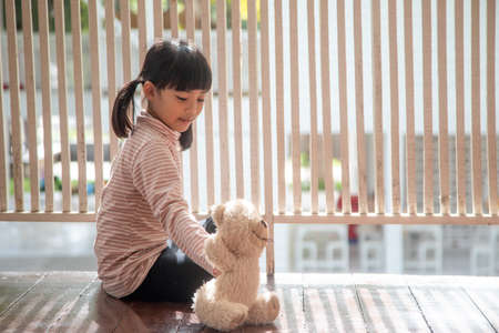 Little girl sitting in the living room with teddy bearの写真素材