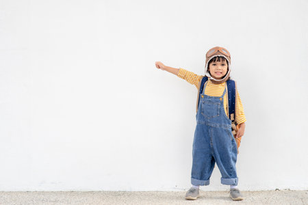 A cute little girl dressed in a cap and glasses of a pilot. The child dreams of becoming a pilot.の写真素材