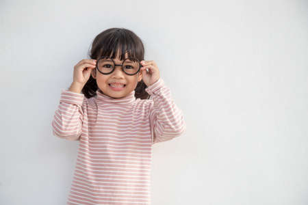 funny Asian child girl wearing glasses on a white backgroundの写真素材