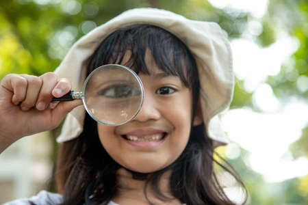 Girl looking through a magnifying glassの写真素材