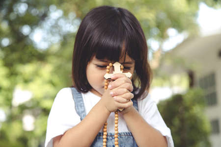 Little Asian girl praying with holding the cross, Christian concept.の写真素材