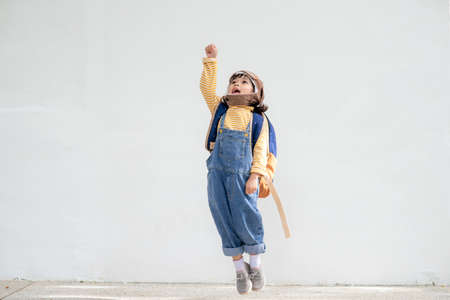 A cute little girl dressed in a cap and glasses of a pilot. The child dreams of becoming a pilot.の写真素材
