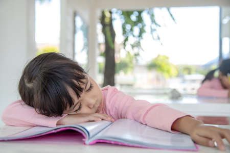 Little Asian girl sleeping on the desk at the classroomの写真素材