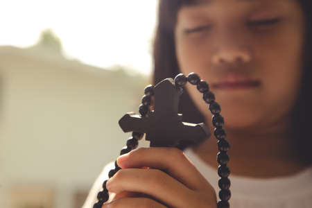 Little Asian girl praying with holding the cross, Christian concept.の写真素材