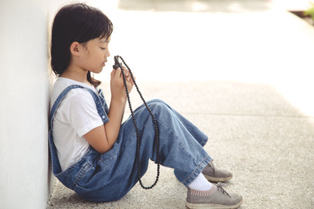 Little Asian girl praying with holding the cross, Christian concept.の写真素材
