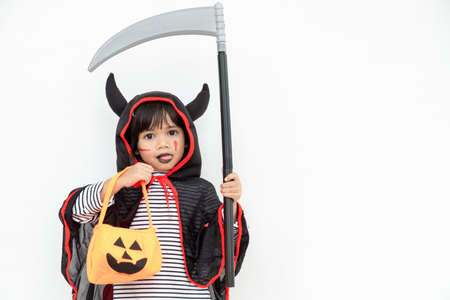 Children girl wearing mysterious Halloween dress holding a scary pumpkin and sickle.の写真素材