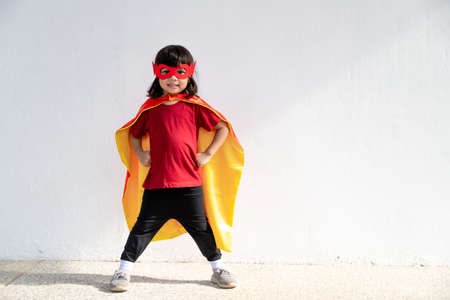 Kids concept, smiling girl playing super hero on white backgroundの写真素材